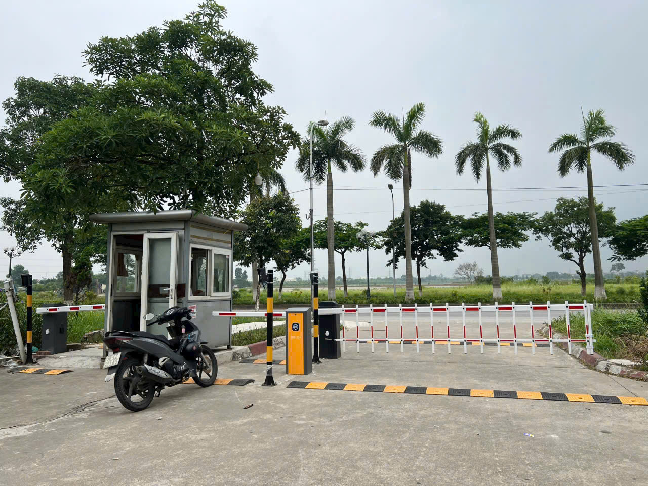 Trạm gác bãi giữ xe với barie tự động và xe máy đỗ trước cổng ra vào
